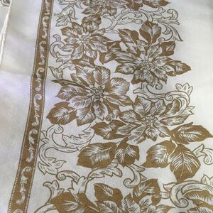 Cream-colored holiday tablecloth with a gold poinsettia motif